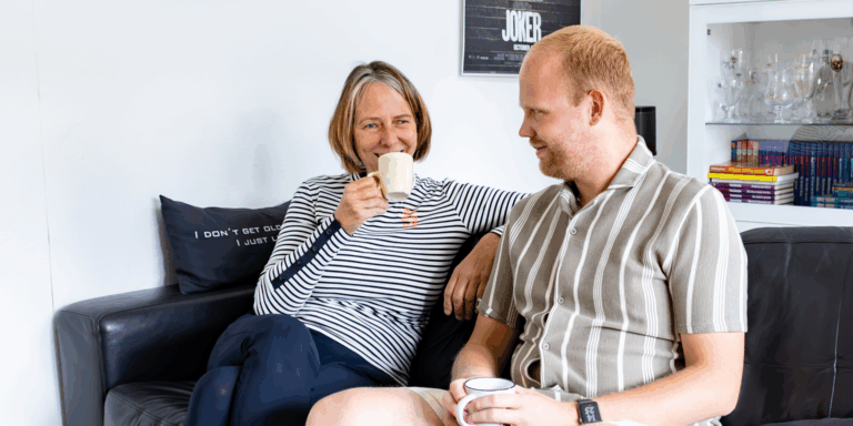 Mantelzorger Marja drinkt samen met haar zoon Bram koffie op de bank
